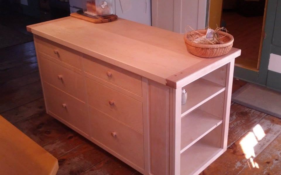 The raised panels along the back of this maple island hide a section of cookbook shelves accessible from the end.