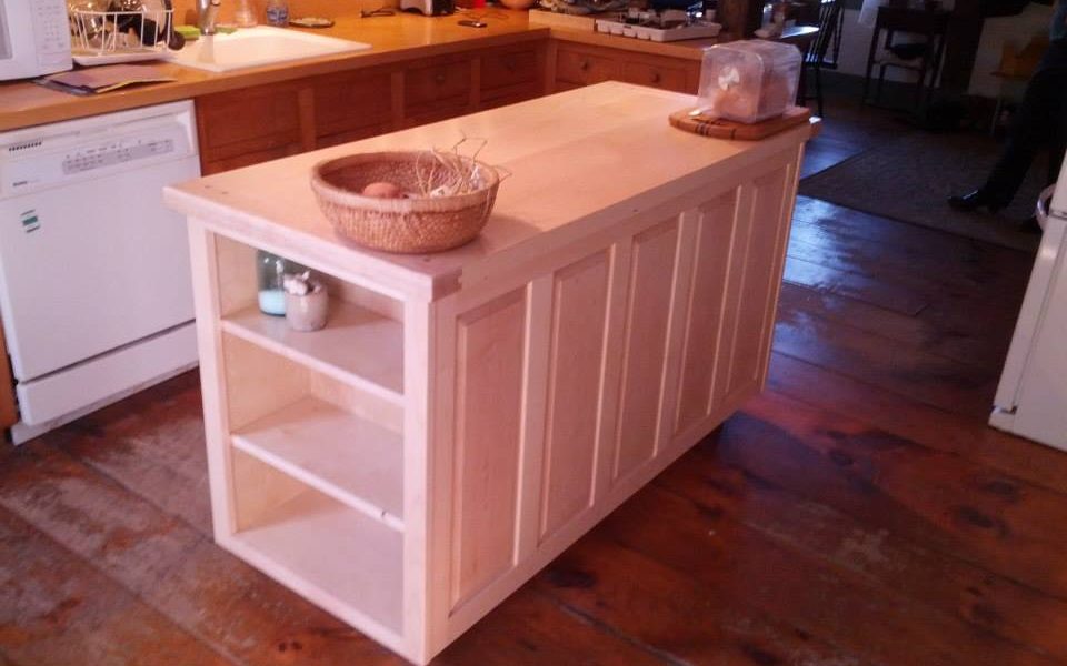 The raised panels along the back of this maple island hide a section of cookbook shelves accessible from the end.