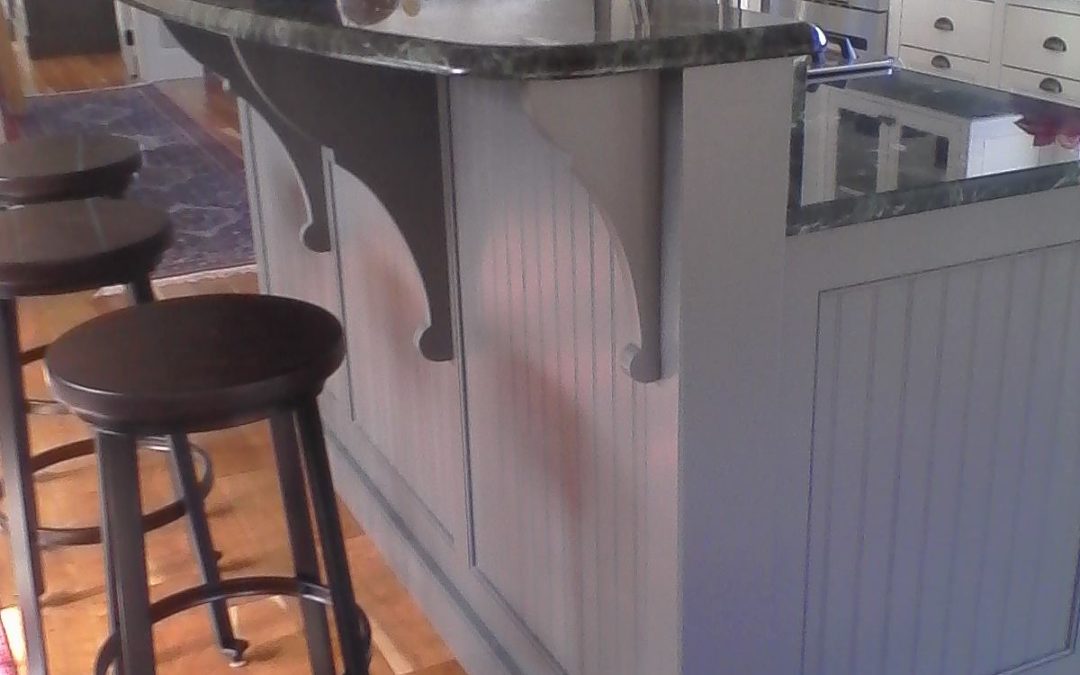 An elliptical stone breakfast bar tops this painted beadboard island.