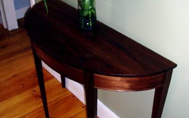 Walnut demilune table with curved and tapered legs.