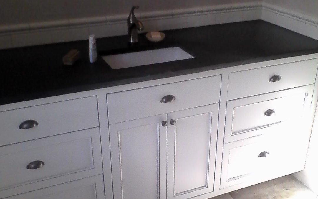 A large white painted vanity with slab and beaded panel drawer fronts and center tip out tray.