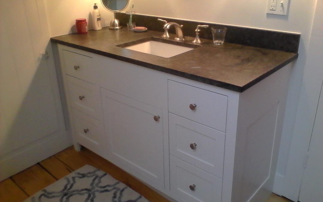 Painted bathroom vanity with slab and paneled drawer fronts.